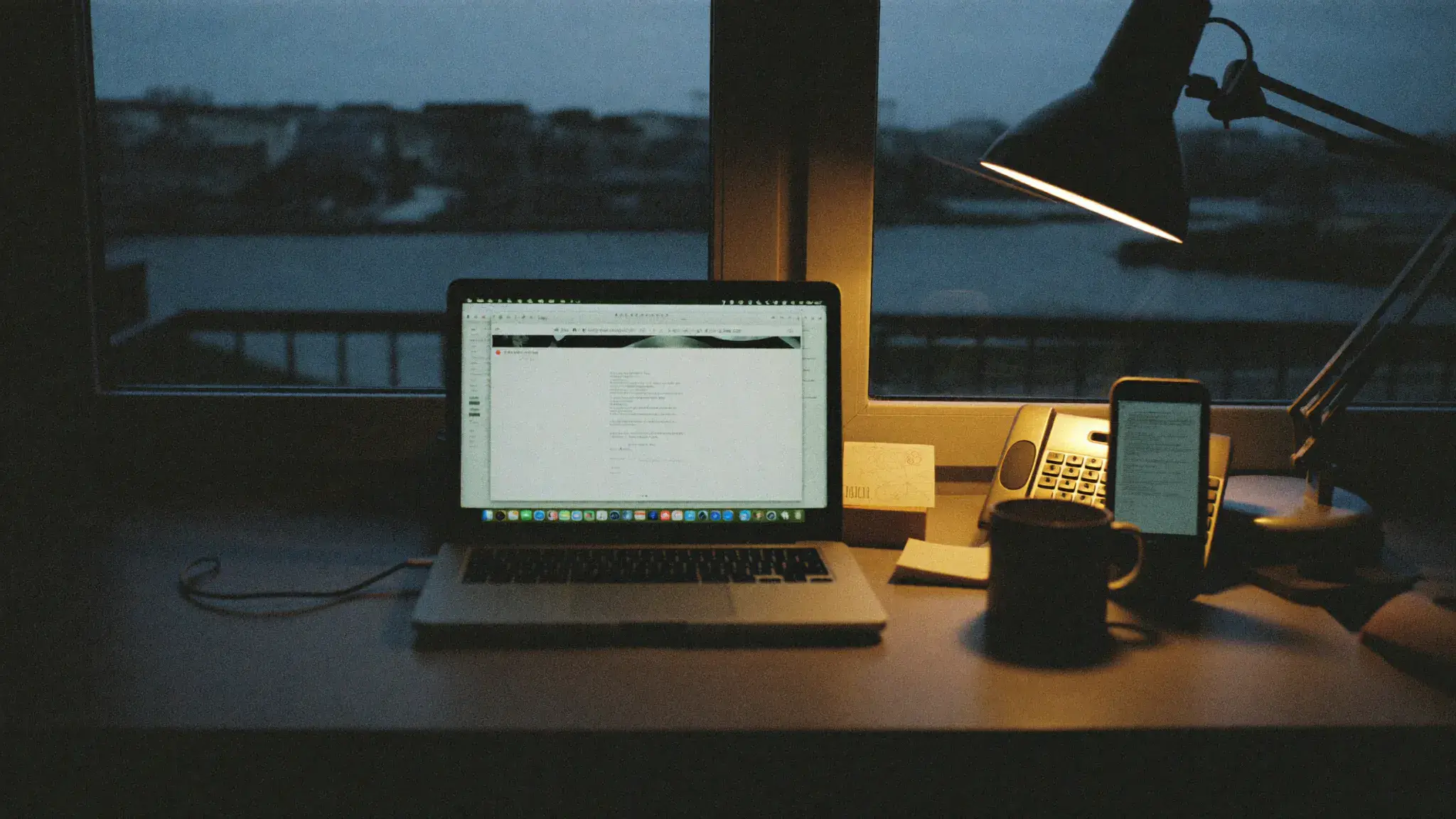 A phone face-up on a desk at night, an enquiry waiting