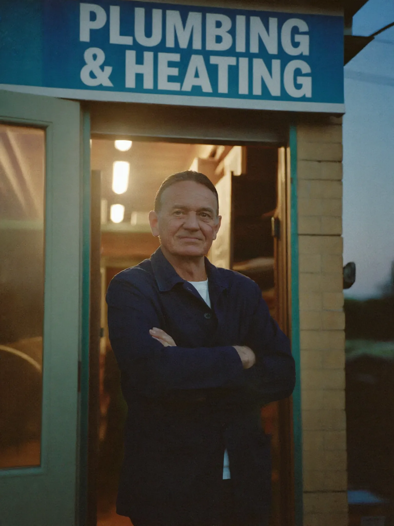 A proud Irish plumber standing at his workshop doorway at dusk